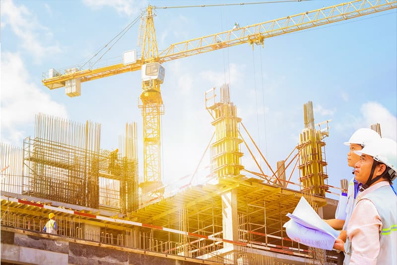 Kỹ sư đội mũ bảo hộ kiểm tra bản vẽ tại công trường xây dựng – minh họa cho việc khảo sát thực tế công trình khi chọn nhà thầu uy tín.