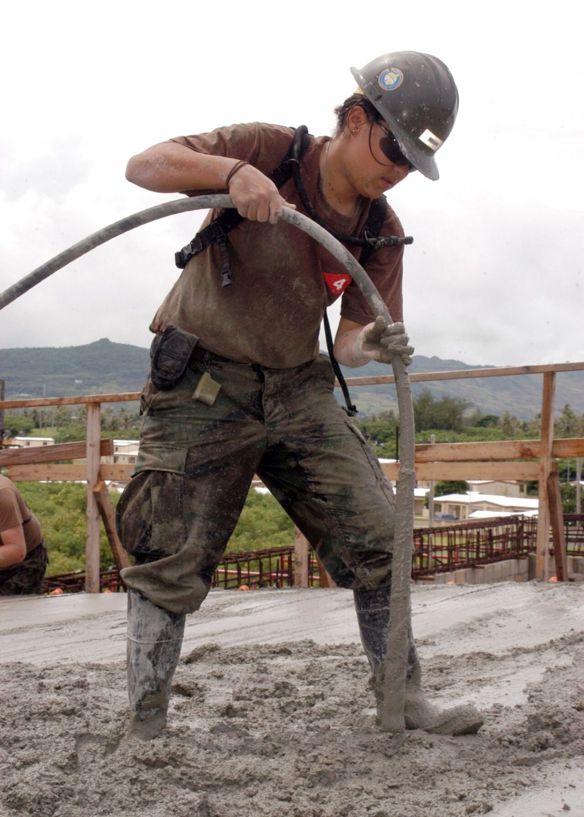 Công nhân dùng đầm dùi làm chặt bê tông khi đổ mái