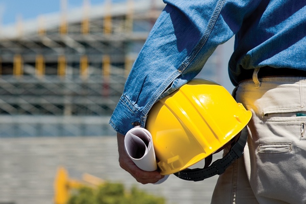 Giám Sát Công Trình Xây Dựng: 7 Bí Quyết Giúp Tránh Sai Lầm Tốn Kém Kỹ sư giám sát công trình cầm mũ bảo hộ và bản vẽ tại công trường