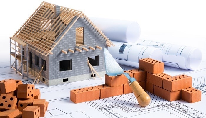 Làm Nhà Cần Chuẩn Bị Gì? Kinh Nghiệm Thực Tế Cho Tổ Ấm Hoàn Hảo Mô hình nhà đang xây dựng và bản vẽ kỹ thuật