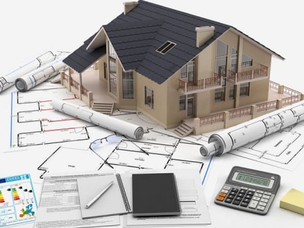 Mô hình nhà và bản vẽ kỹ thuật trong quá trình thiết kế kiến trúc nhà ở, với tài liệu, máy tính và công cụ tính toán chi phí đi kèm.