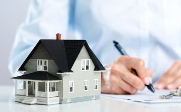 Xây Nhà Cần Chuẩn Bị Gì? 6 Bước Quan Trọng Giúp Bạn Không Vỡ Kế Hoạch Người ký giấy tờ bên cạnh mô hình nhà thể hiện thủ tục pháp lý xây nhà